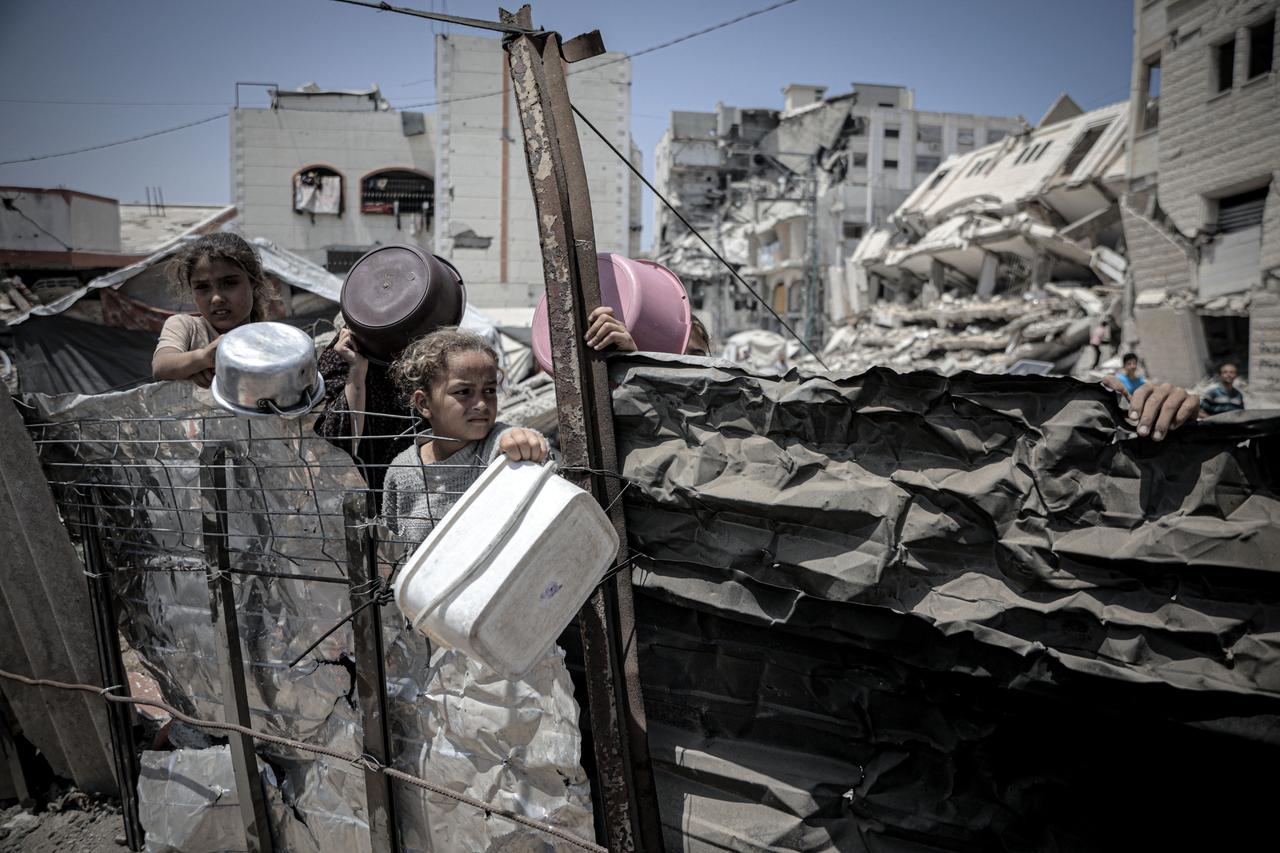 GAZA CITY, GAZA - MAY 31: Palestinians including women and children living in tents receive food distributed by aid organizations in al Mawasi district of Khan Yunis, Gaza on May 30, 2025. The situation highlights the growing desperation and urgent need for humanitarian assistance in the region. ( Ahmed Jihad Ibrahim Al-arini - Anadolu Agency )