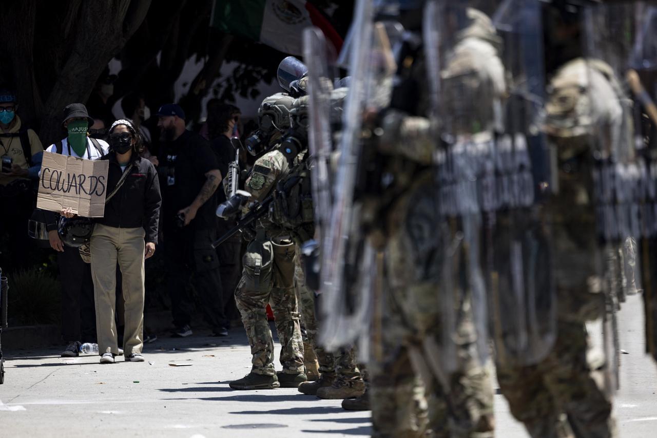 A demonstrator holds a poster reading “Cowards” in front of National guards during clashes with law enforcement in front of the federal building during a protest following federal immigration operations, in Los Angeles, California on June 8, 2025. (AFP Photo)