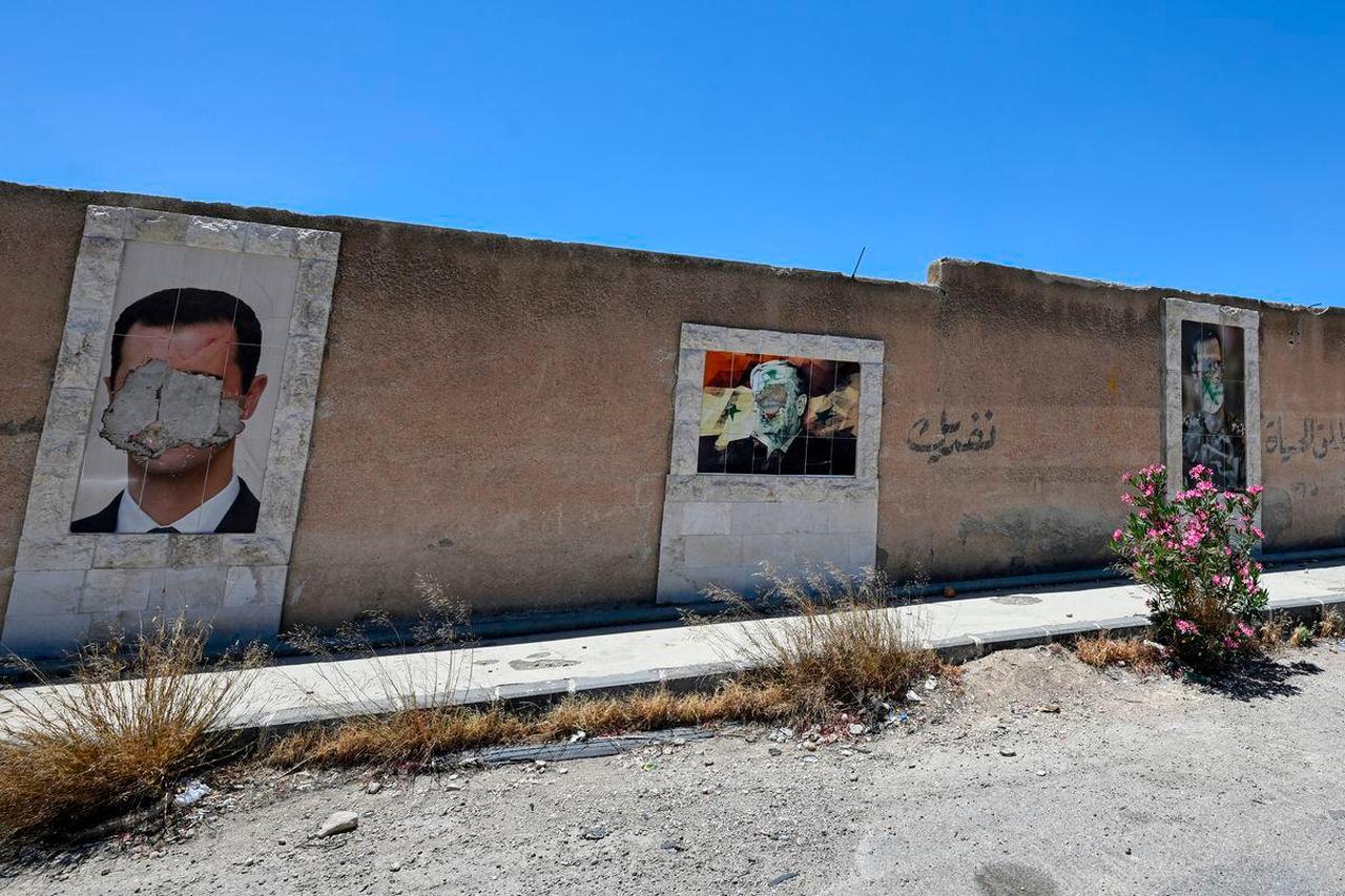 Defaced portraits of Syria's ousted president Bashar al-Assad (L) and his late father Hafez al-Assad (C) hang on a wall in the capital Damascus on June 2, 2025. (AFP Photo)