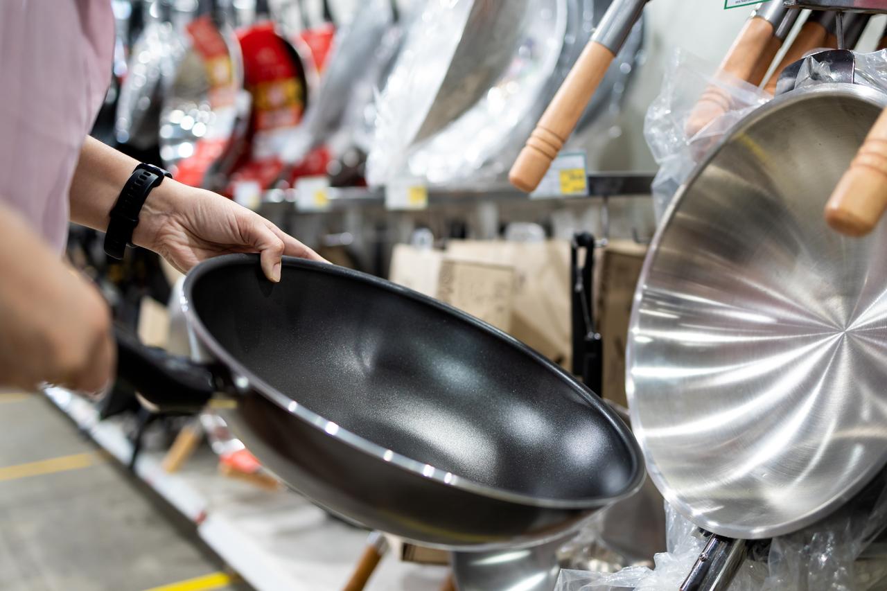 A shopper examines a non-stick frying pan at a housewares aisle in a UK retail store, accessed on June 21, 2025. (Adobe Stock Photo)