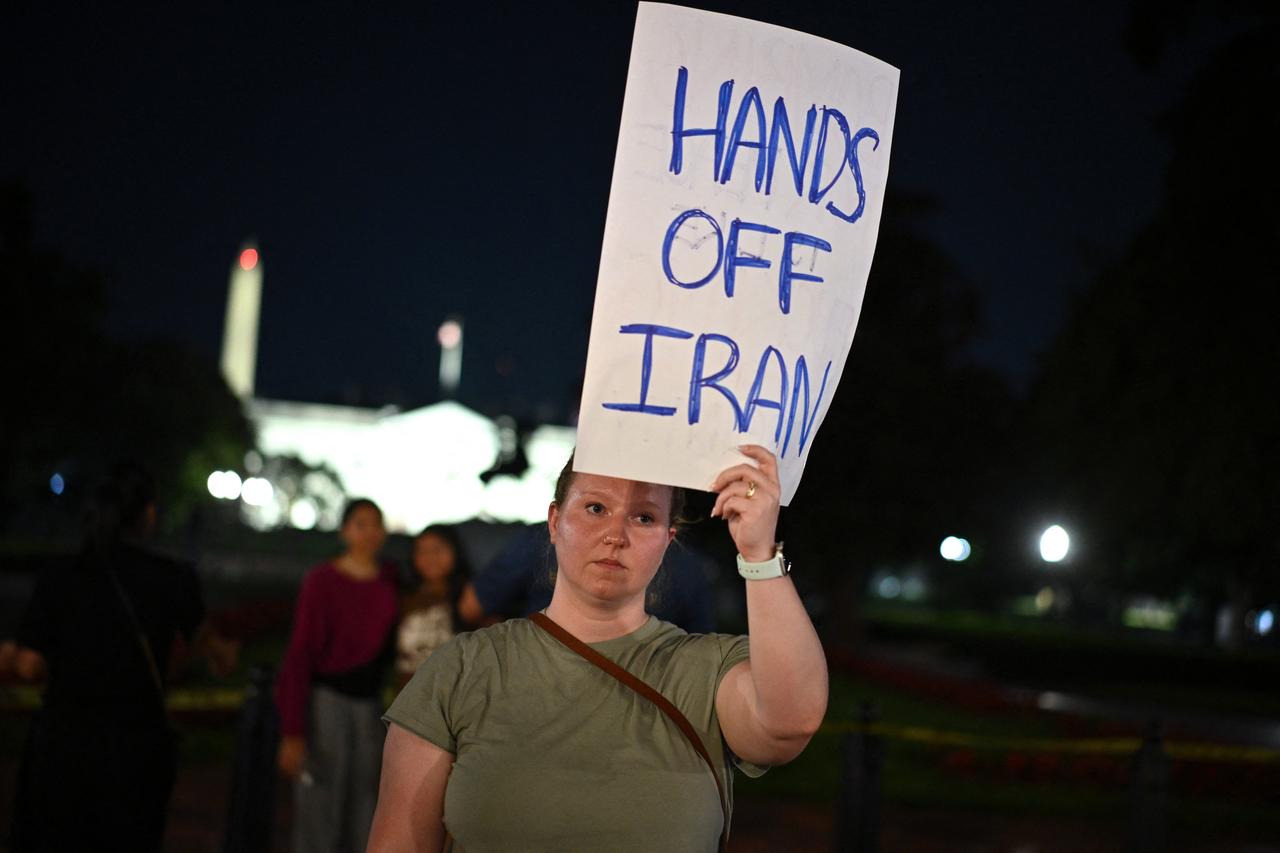 A protestor holds a sign at Lafayette Square outside The White House in Washington, DC, on June 21, 2025. (AFP Photo)