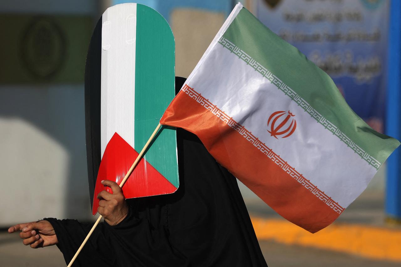 An Iraqi woman carries the flags of Iran and Palestine during a march in the Kadhimiya district of Baghdad on June 21, 2025, to protest against Israels strikes on Iran. (AFP Photo)