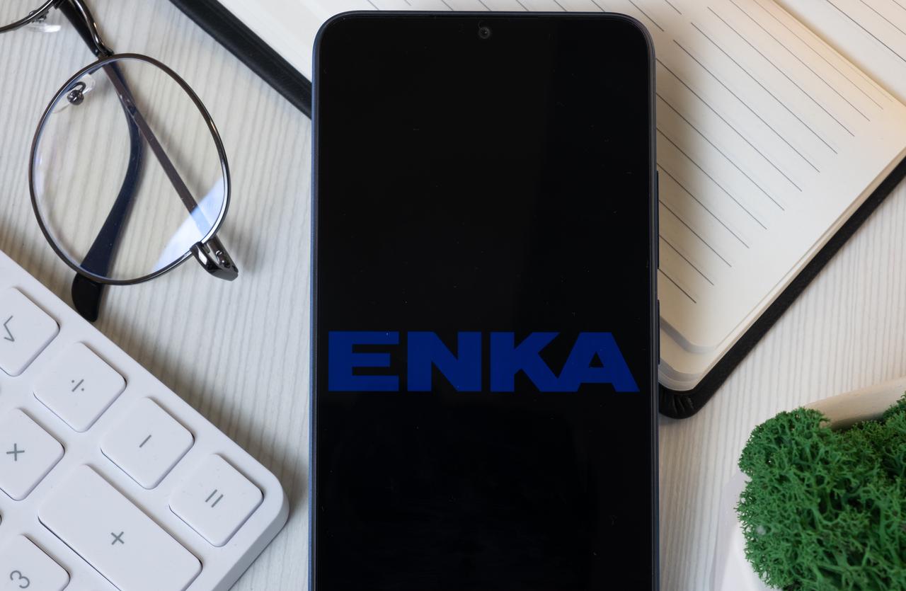 A smartphone displays the logo of Turkish engineering and construction giant ENKA, seen alongside office supplies in New York, USA, on June 11, 2024. (Adobe Stock Photo)