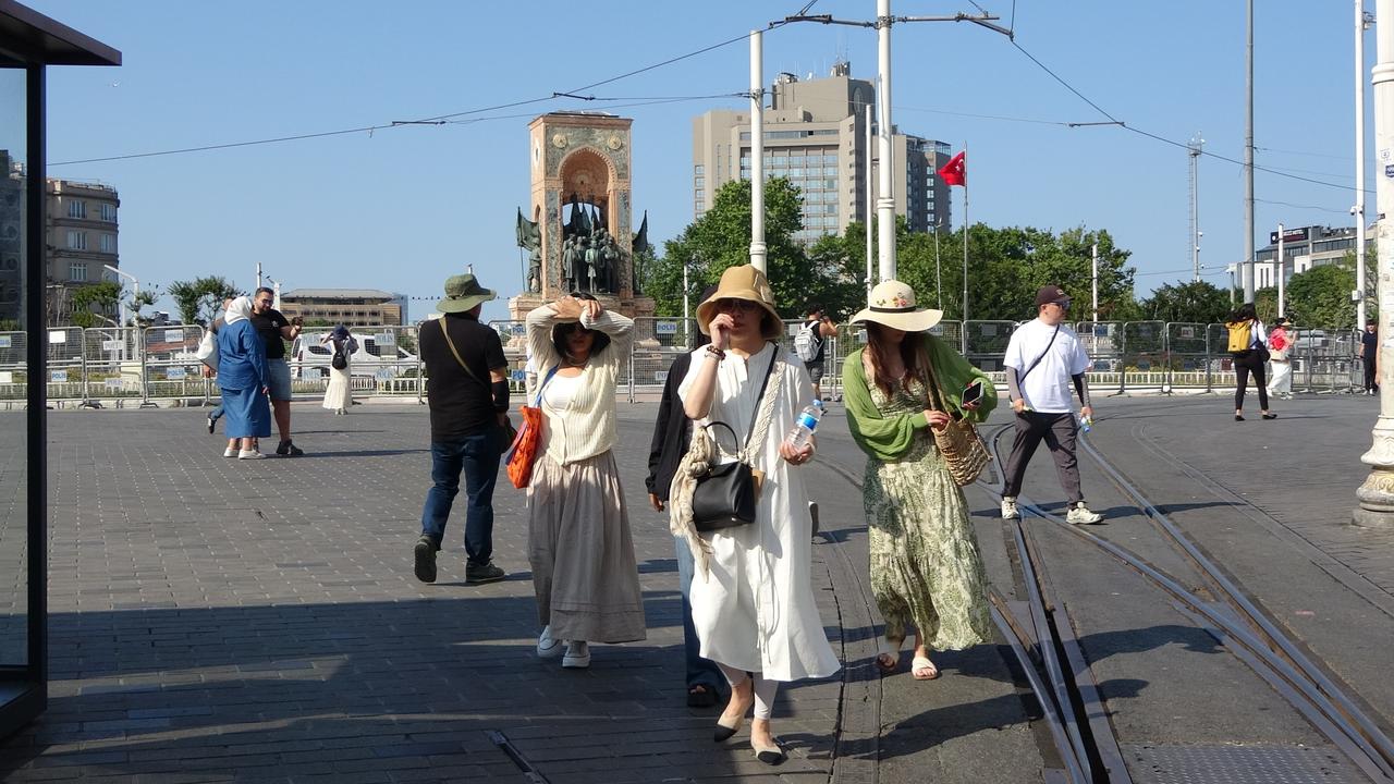 Tourists seek shade from the sun as they walk through Taksim Square in Istanbul, Türkiye, amid sweltering heat, June 18, 2025. (IHA Photo)