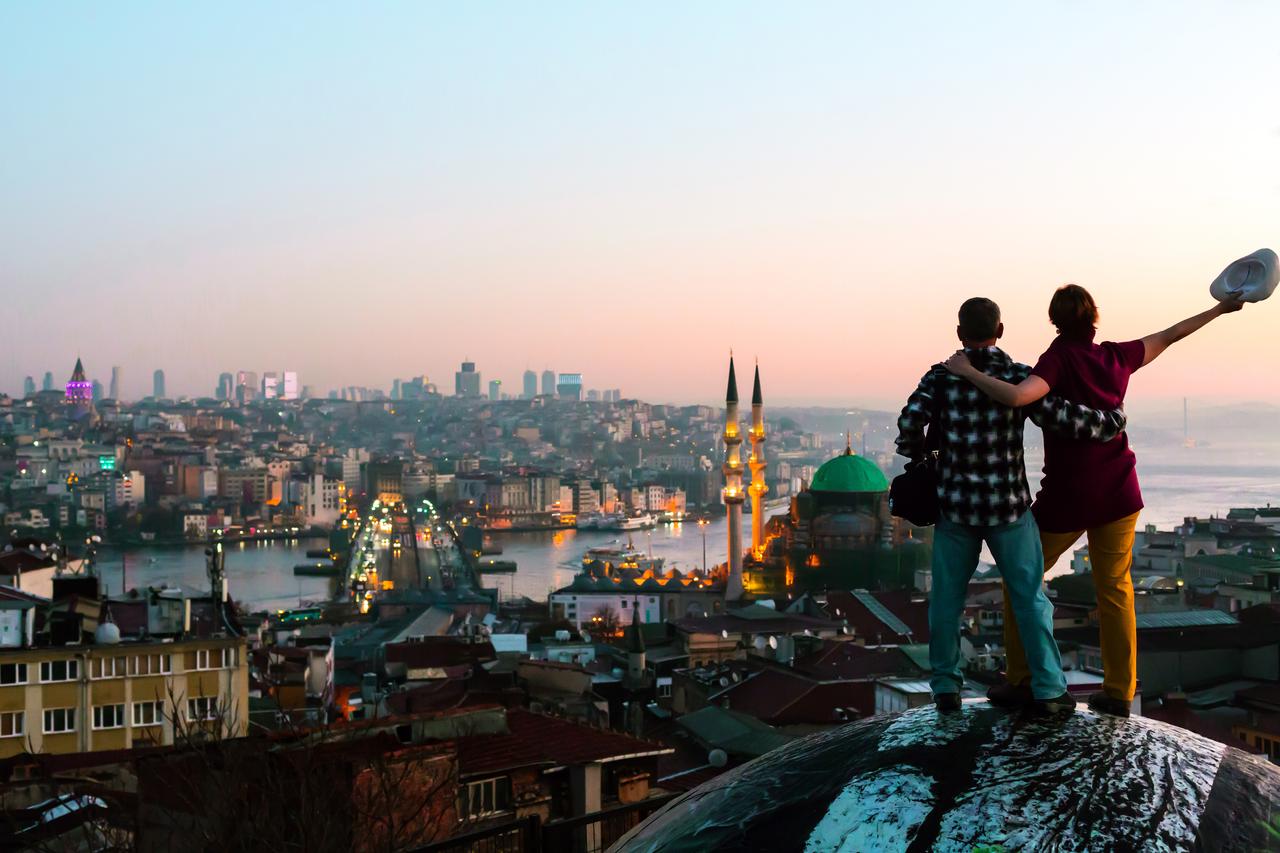Tourists admire the sunset over Istanbuls Golden Horn, with Galata Tower and the citys skyline in view, Türkiye, accessed June 25, 2025. (Adobe Stock Photo)