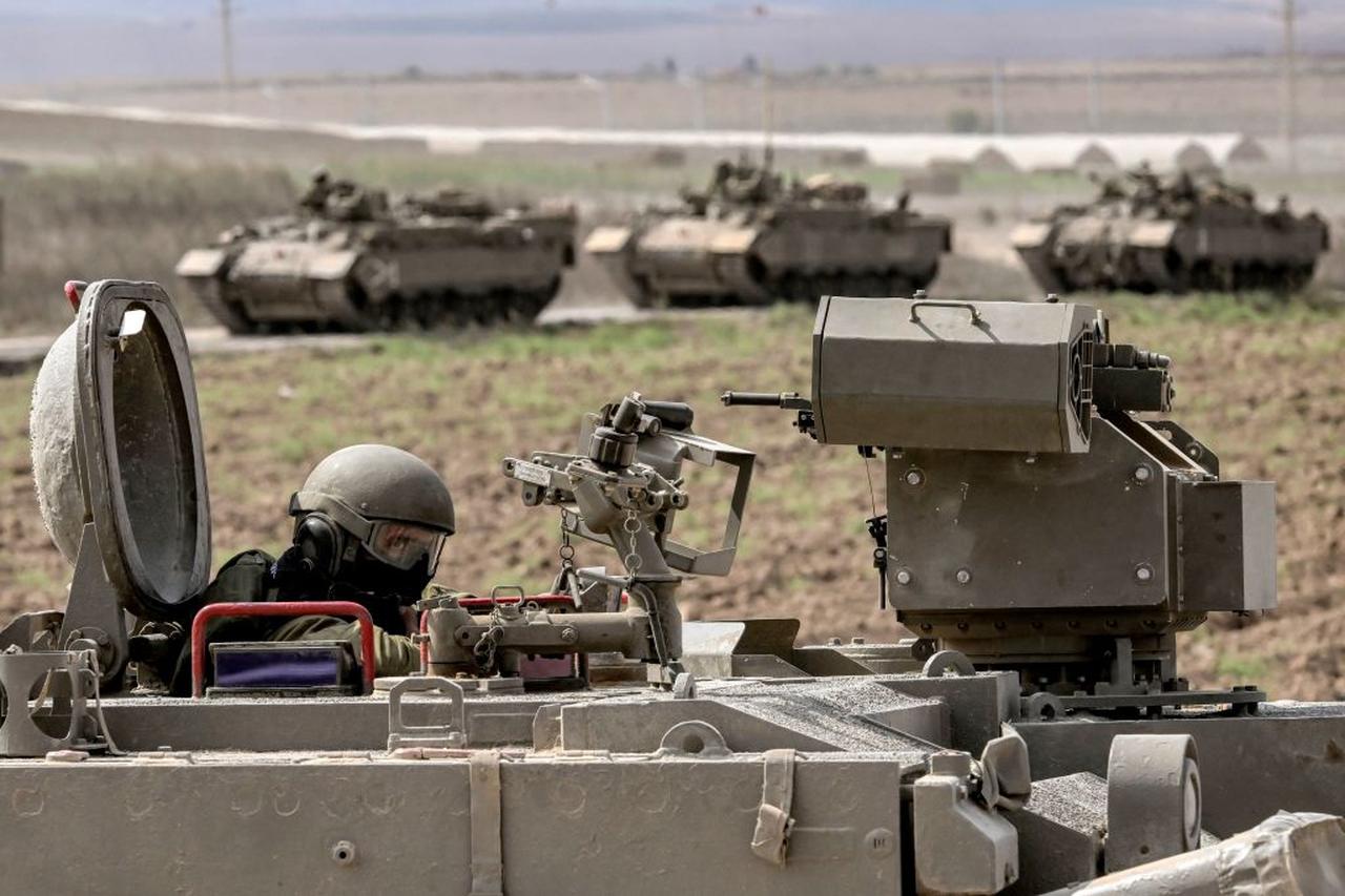 An Israeli army soldier sits in the hatch of a Puma armoured personnel carrier (APC) in a column with other vehicles near the Gaza border in southern Israel on October 14, 2023. (AFP Photo)