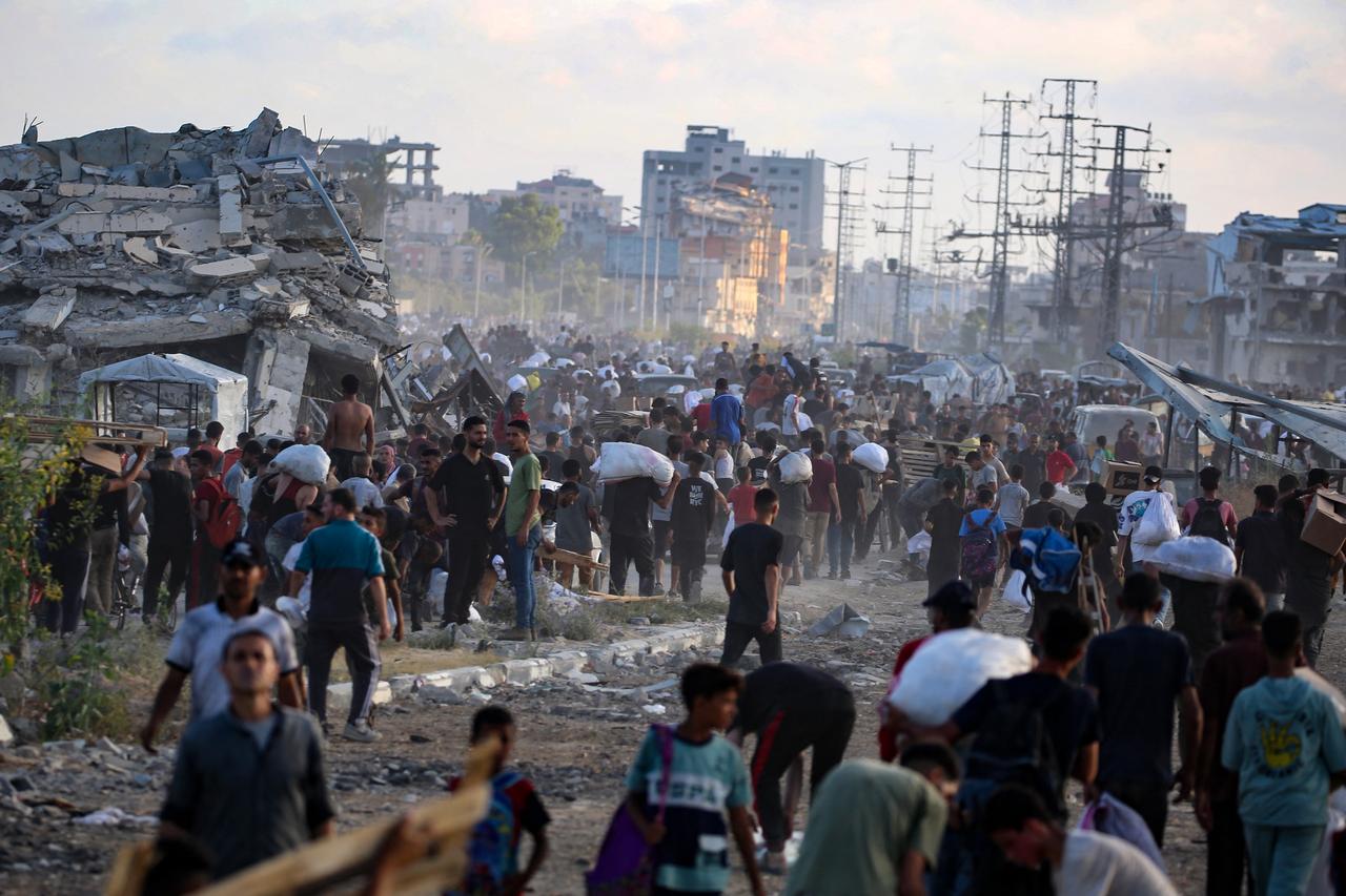 People, some carrying aid parcels, walk along the Salah al-Din road near the Nusseirat refugee camp in the central Gaza Strip on June 25, 2025. (AFP Photo)