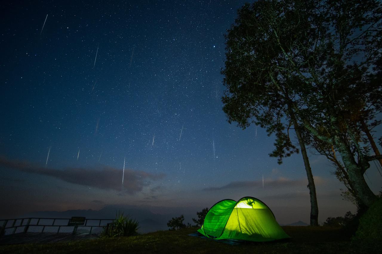Meteors streak across the night sky during the Geminid meteor shower above a glowing green camping tent, accessed Jun. 27, 2025. (Adobe Stock Photo)
