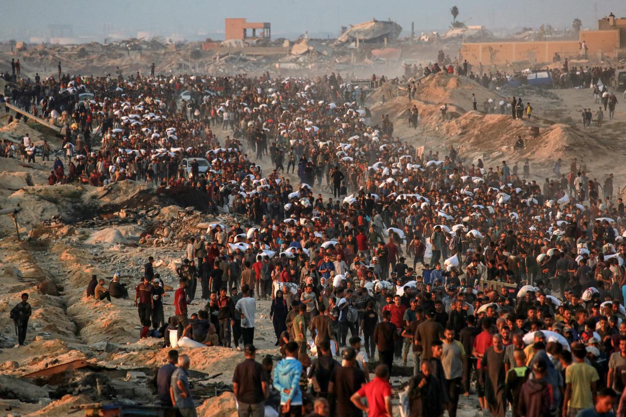 People carrying sacks of flour walk along al-Rashid street in western Jabalia on June 17, 2025. (AFP Photo)