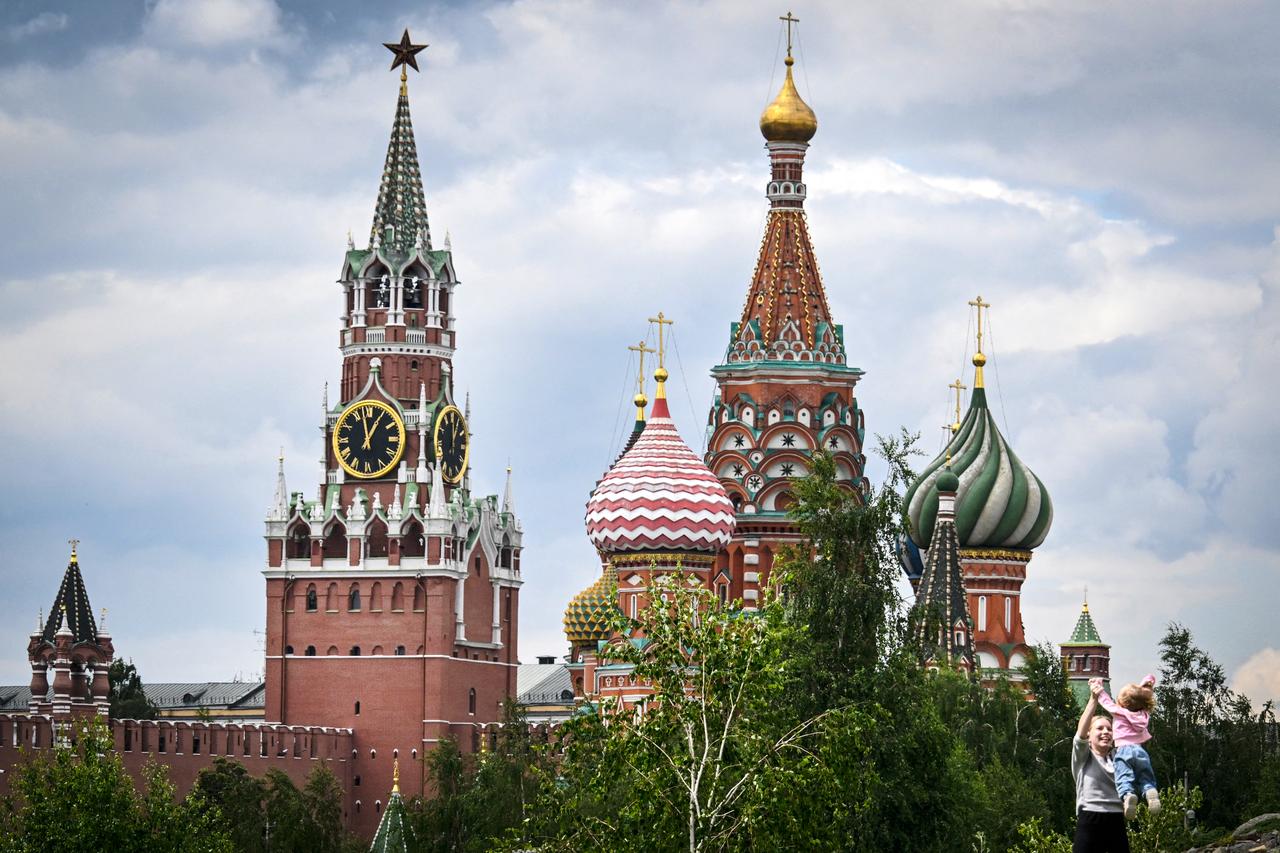A family plays in front of the Kremlins Spasskaya tower and St. Basils cathedral in downtown Moscow on June 23, 2025. (AFP Photo)