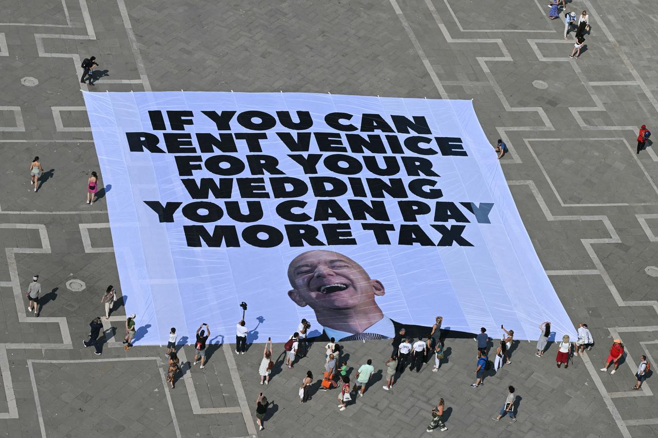 Activists of international environmental group Greenpeace deploy a giant banner displaying a picture of Jeff Bezos and reading "If you can rent Venice for your wedding you can pay more tax" at St Mark square  in Venice, Italy, on June 23, 2025. (AFP Photo)