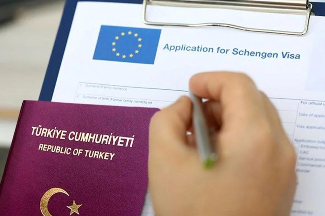 A Turkish passport placed over a Schengen visa application form as a person fills it out. (Stock Photo)