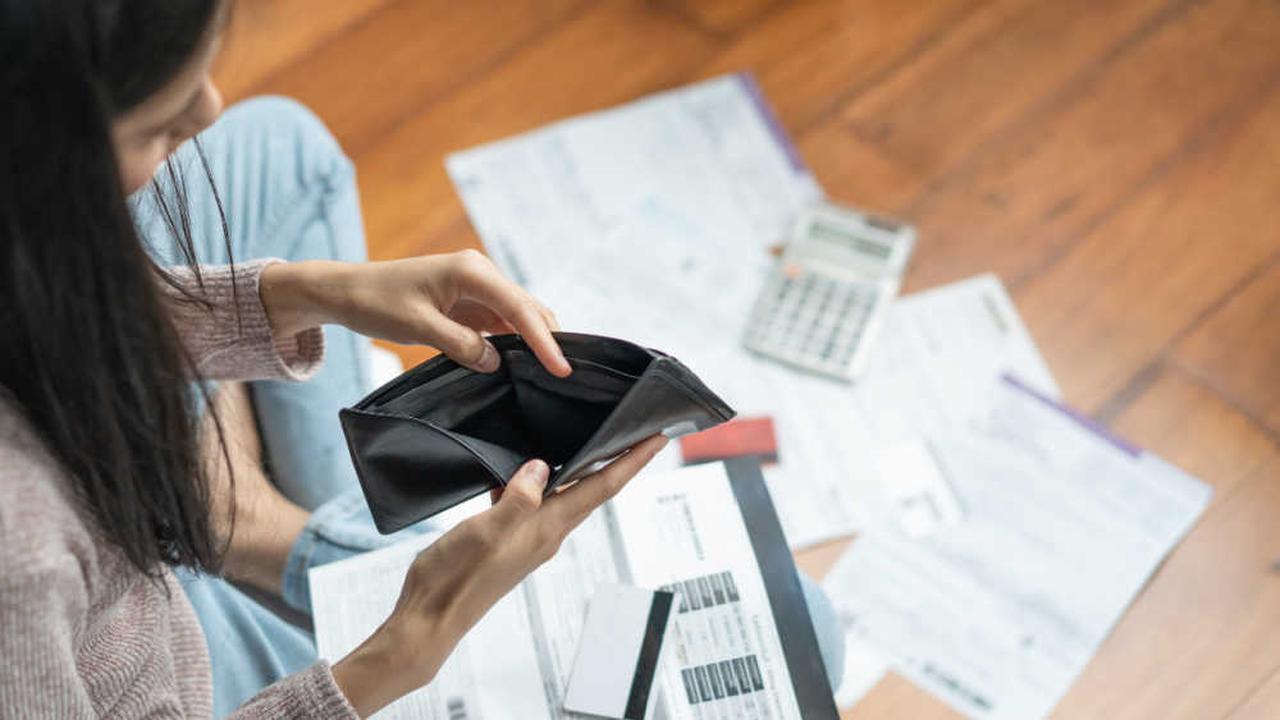 File photo shows a woman checking her empty wallet while surrounded by unpaid bills and a calculator, accessed on June 27, 2025. (Adobe Stock Photo)