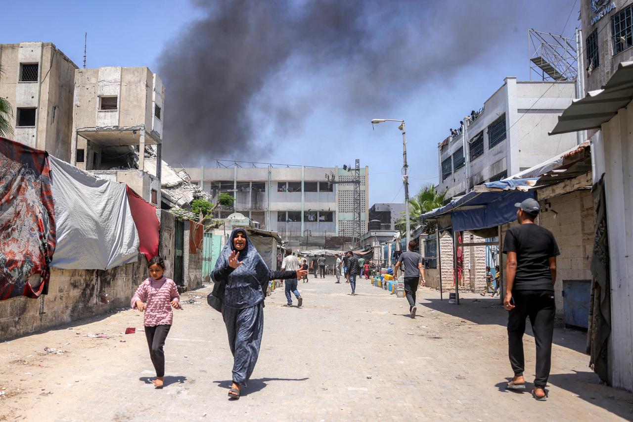People walk away as smoke erupts from a fire following an Israeli strike at the UNRWA's Osama bin Zaid school in the Saftawi district in western Jabalia in the northern Gaza Strip on June 27, 2025. (AFP Photo)