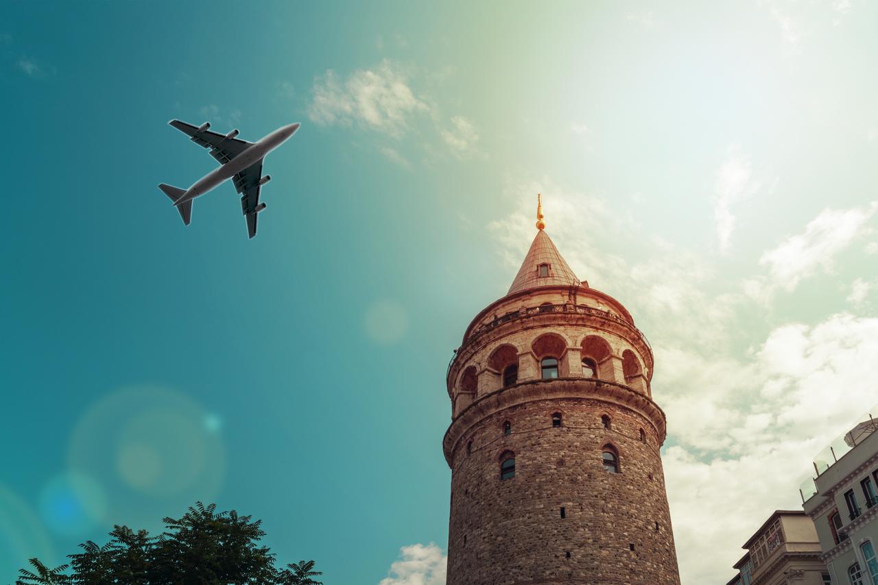 A plane flies over Galata Tower during peak travel season as tourists arrive in Istanbul amid ongoing heat warnings, Istanbul, Türkiye, accessed on Jun. 28, 2025. (Adobe Stock)