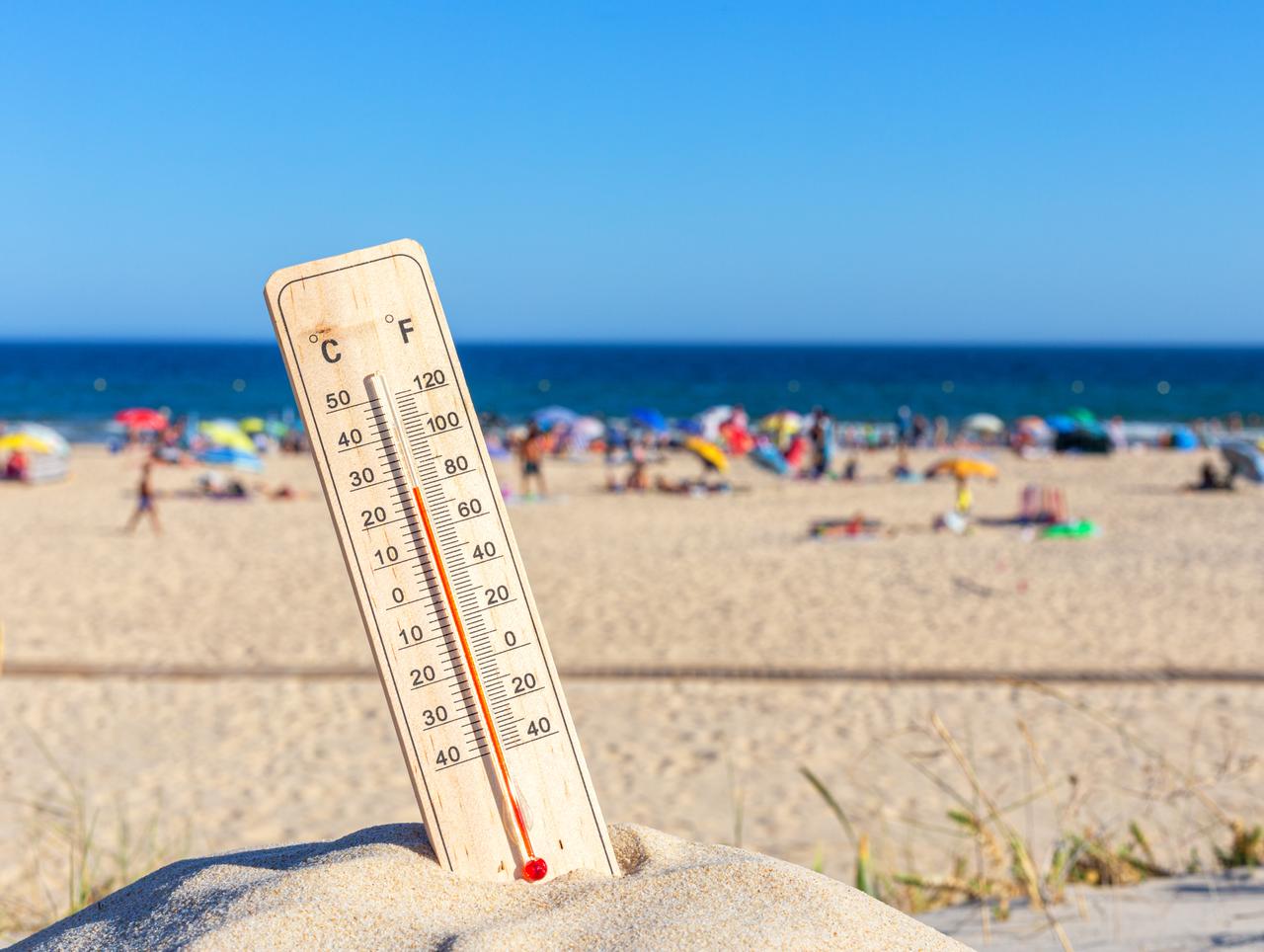A thermometer placed in beach sand shows soaring temperatures during midday hours as crowds fill the coast, Aegean coast, Türkiye, accessed on Jun. 28, 2025. (Adobe Stock)