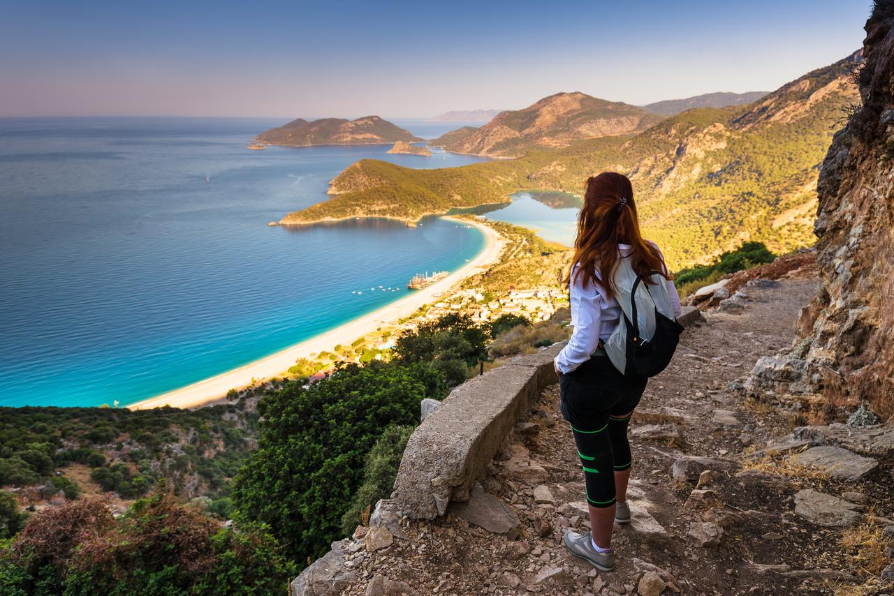 A hiker pauses above Oludeniz Bay, where early morning hours remain the safest time to explore before peak heat, Mugla, Türkiye, accessed on Jun. 28, 2025. (Adobe Stock)