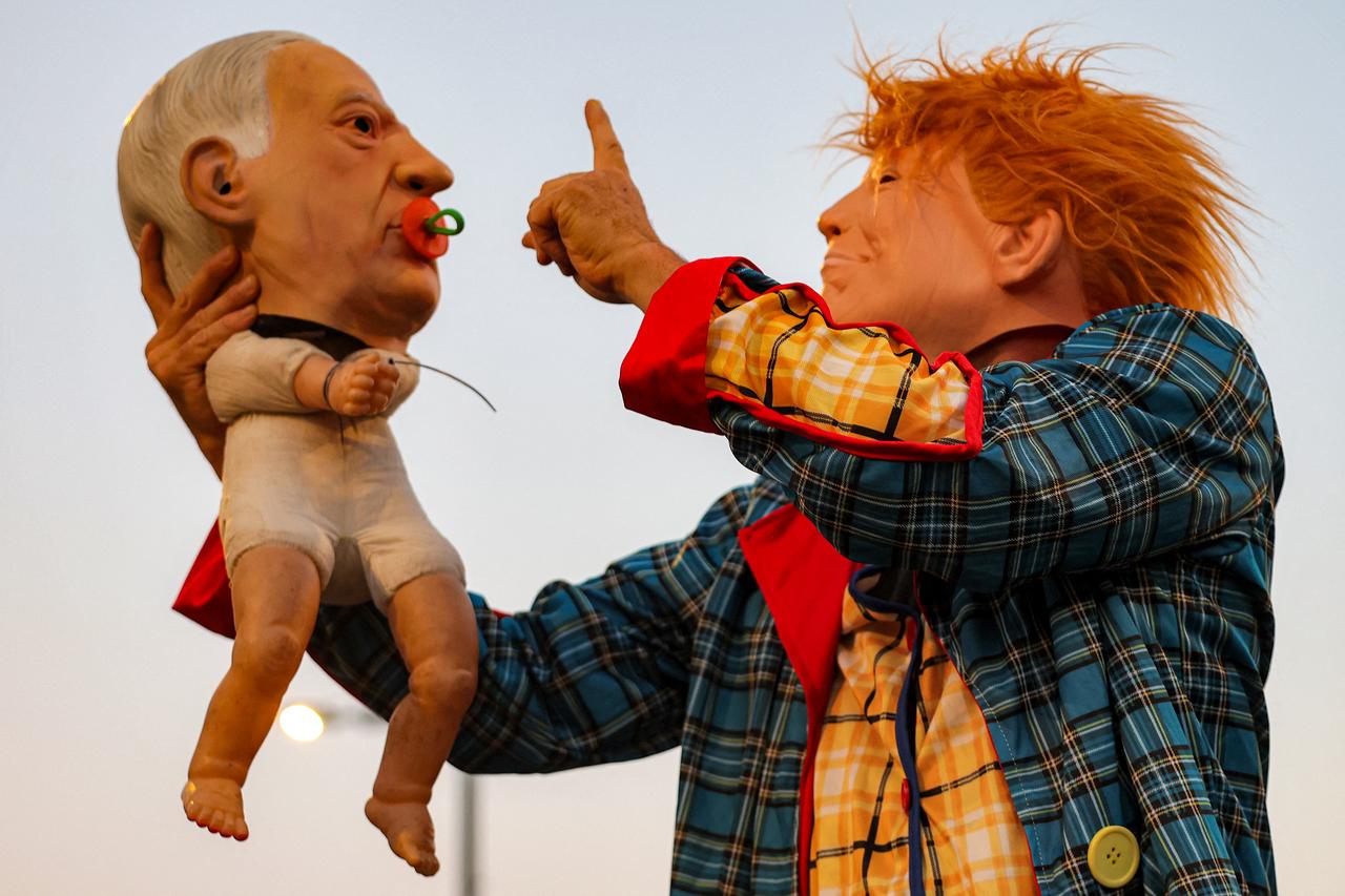 A demonstrator in a clown costume with a mask depicting US President Donald Trump holds a baby puppet depicting Israel's Prime Minister Benjamin Netanyahu during an anti-government protest calling for action to secure the release of Israeli hostages, outside the Israeli Defence Ministry headquarters in Tel Aviv on June 28, 2025. (AFP Photo)