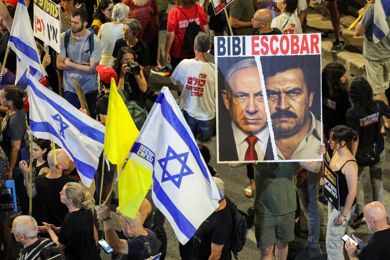 A demonstrator holds a sign depicting a mashup of the faces of Israeli Prime Minister Benjamin Netanyahu and late Colombian drug lord Pablo Escobar during an anti-government protest calling for action to secure the release of Israeli hostages, outside the Israeli Defence Ministry headquarters in Tel Aviv on June 28, 2025. (AFP Photo)