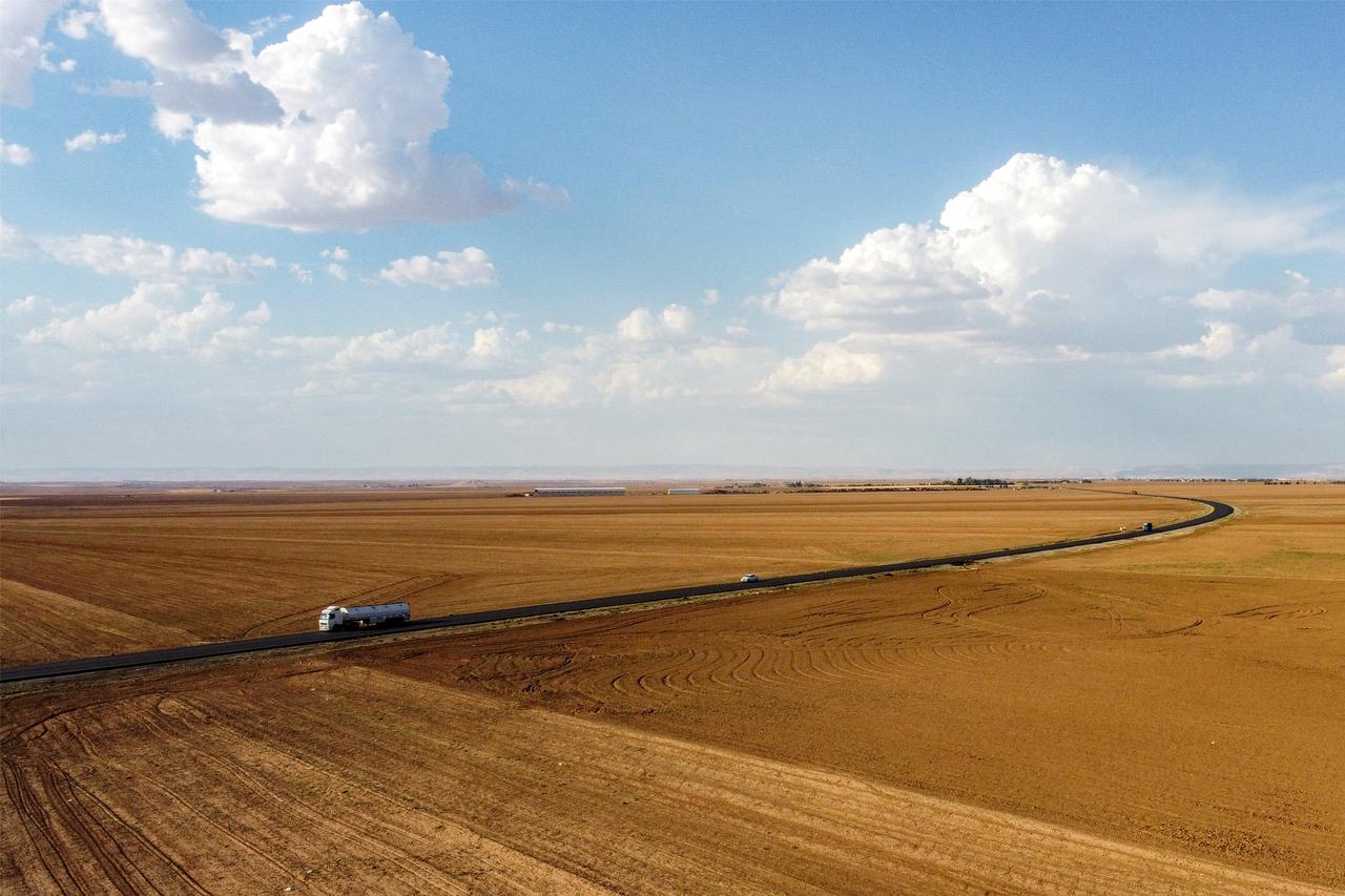 This aerial view shows vehicles moving along a road surrounded by agricultural fields on the outskirts of Qamishli in northeastern Syria, on June 3, 2025. (AFP Photo)