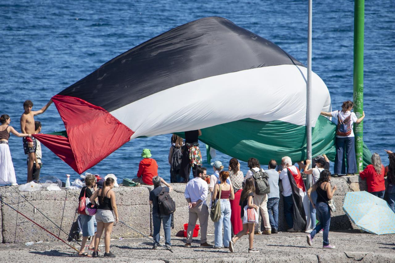 A huge Palestinian flag is seen as the humanitarian organization Freedom Flotilla Coalition is in Catania from where the ship Madleen set sail on June 1, 2025. (AA Photo)