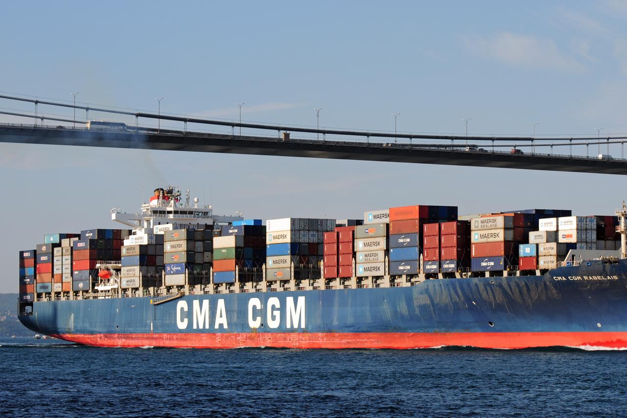 A cargo ship loaded with containers sails under the Bosphorus Bridge in Istanbul, Türkiye, on October 2, 2011. (Adobe Stock Photo)