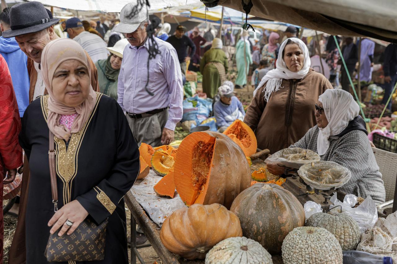 A couple walks past a pumpkin sellers stall at the weekly market in Khemisset in the Rabat region, about 100 kilometres east of the Moroccan capital, on June 3, 2025, as people shop for preparations ahead of Eid al-Adha, the Muslim feast of sacrifice. (Photo by Abdel Majid BZIOUAT / AFP)