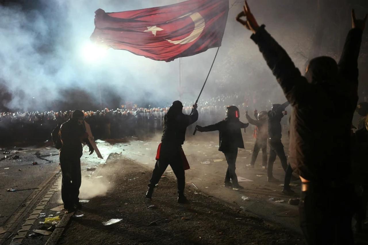 A protestor waves a Turkish flag in front of police during a rally in support of Istanbuls arrested mayor in Istanbul, Türkiye on March 24, 2025. (AFP Photo)