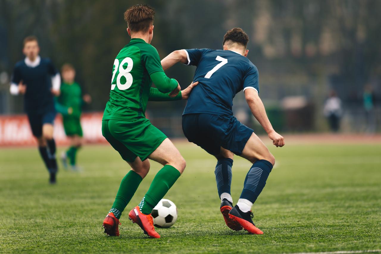 Two footballers in action during a football match at the stadium. (Adobe Stock Photo)