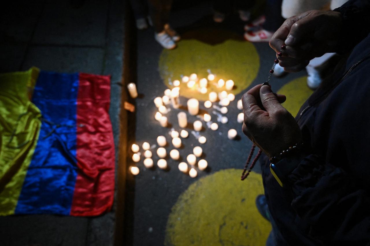 A man holds a crucifix as he prays outside the Clinic Fundación Santa Fe, where Senator Miguel Uribe Turbay is receiving medical treatment after being shot and wounded in Bogota on June 7, 2025. (AFP Photo)