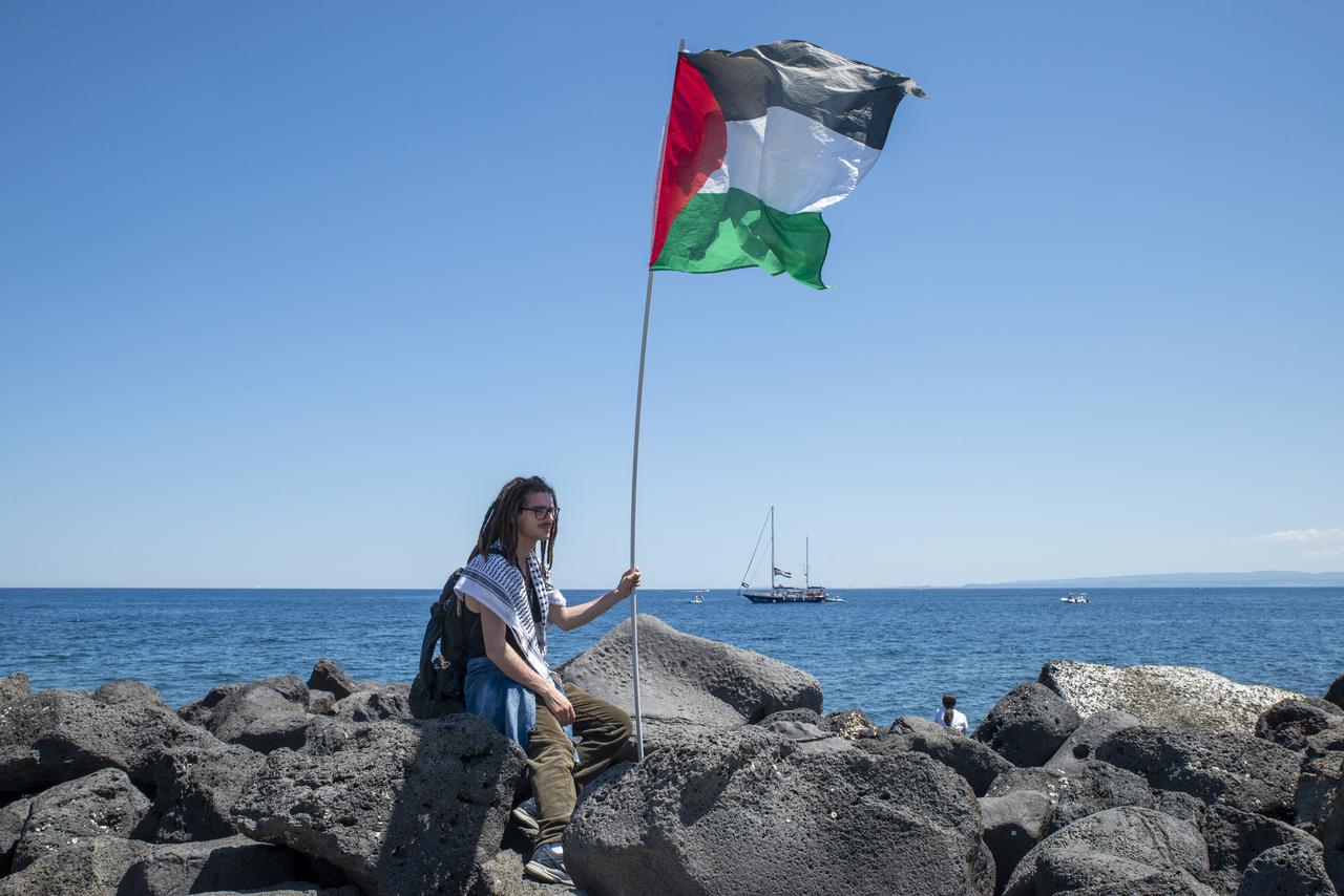 A man holds a Palestinian flag as the humanitarian organization Freedom Flotilla Coalition is in Catania from where the ship Madleen will depart on its mission to break the siege on Gaza, in Catania, Italy on June 01, 2025. (AA Photo)
