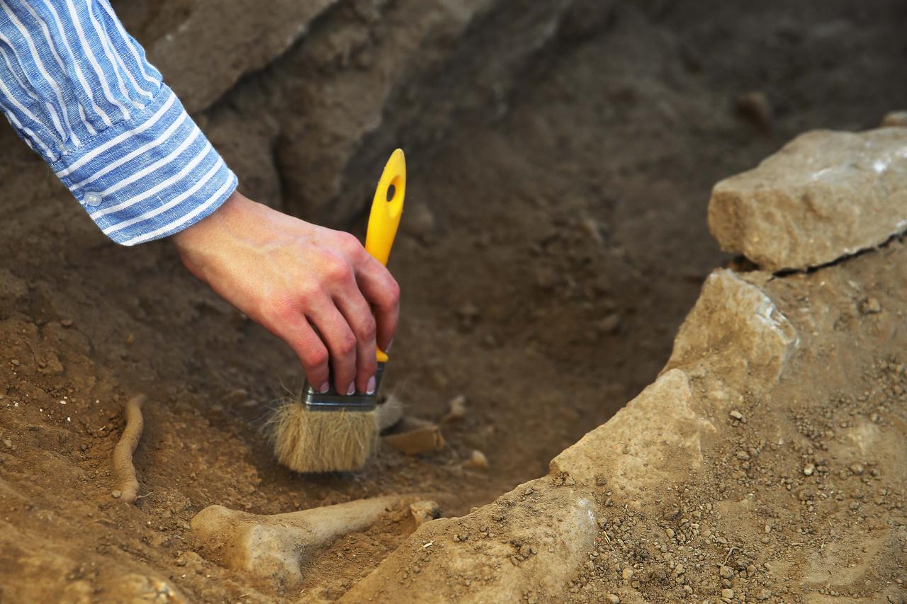 An archaeologist works to unearth one of numerous Byzantine-era child and adult graves in the ancient city of Herakleia, in Milas, Mugla, Türkiye, July 11, 2025. (AA Photo)