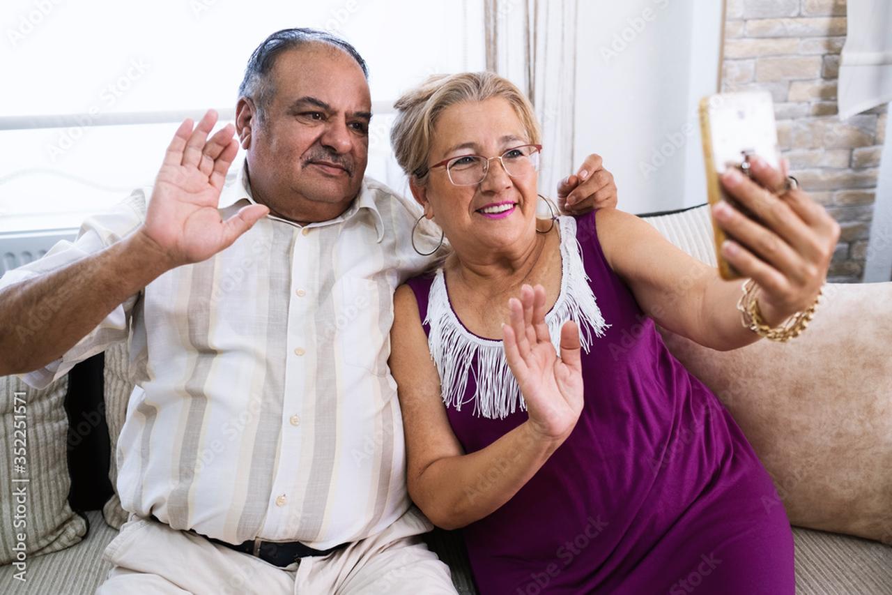 An elderly couple waves while speaking on a video call from their home in Türkiye. (Adobe Stock Photo)
