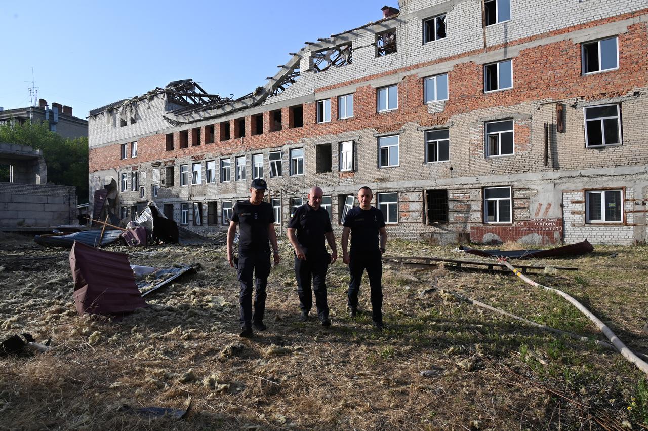 Rescue workers walk outside an unfinished residential building damaged after a drone attack, in central Kharkiv on July 11, 2025. (AFP Photo)