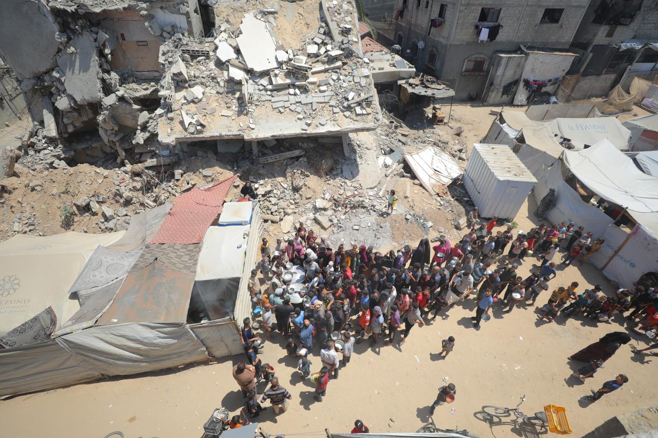 Many Palestinians, including children, line up to receive food in Deir al- Balah city, Gaza on July 14, 2025. (AA Photo)