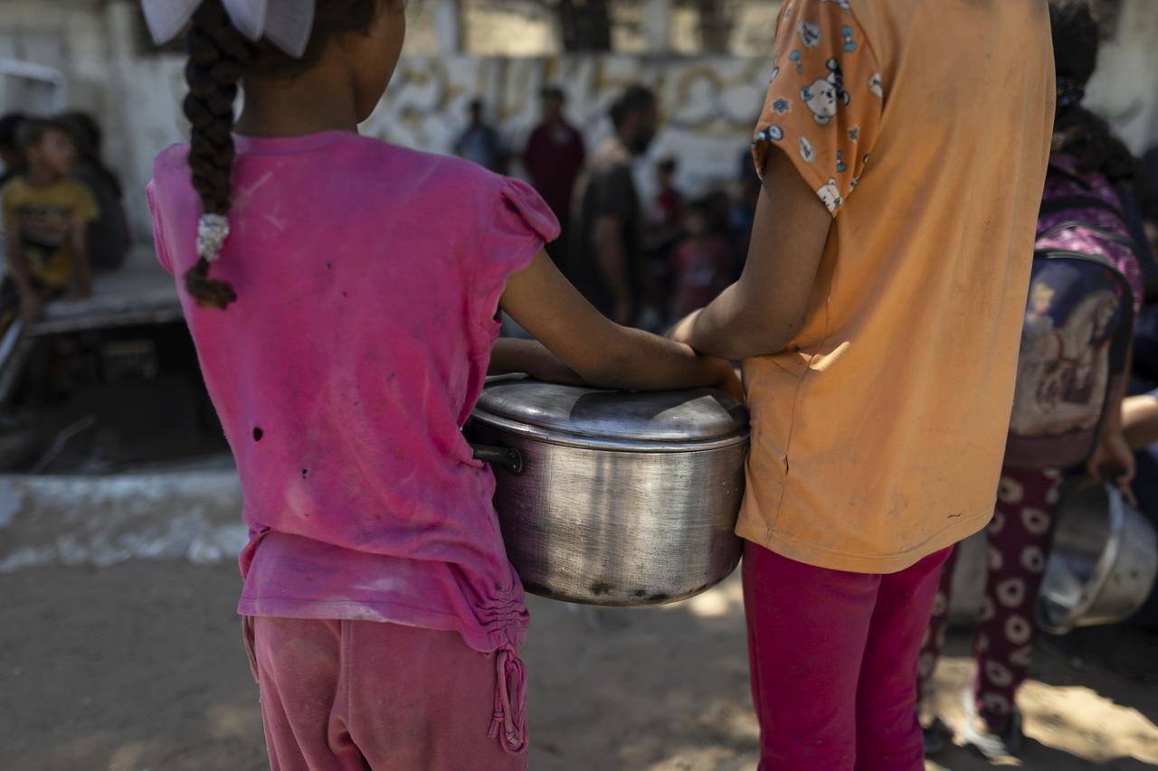 Palestinian children hold a pot while waiting to receive food distributed by a charity in the Al-Rimal neighborhood on Gaza on July 11, 2025. (AA Photo)