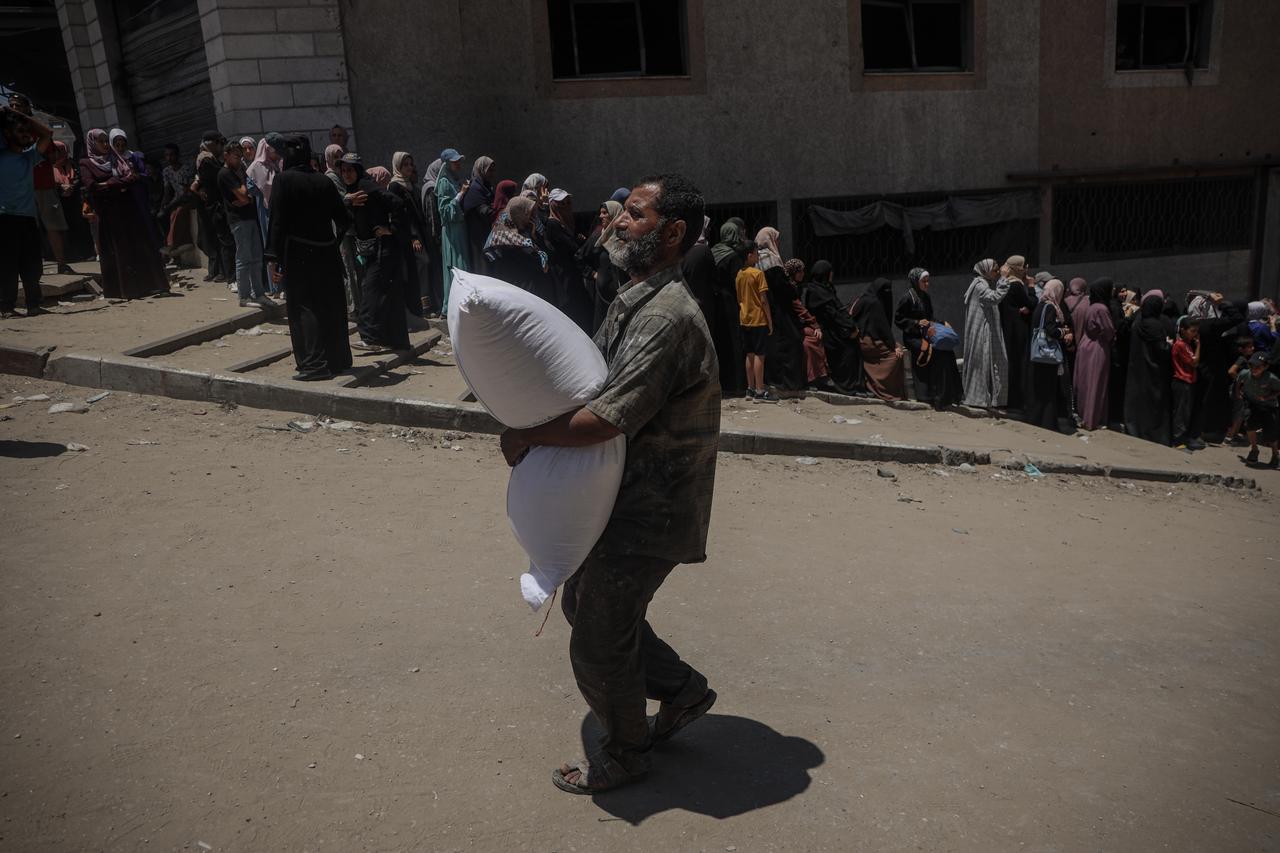 Palestinians gather at the distribution center to receive humanitarian aid supplies in Gaza on July 12, 2025. (AA Photo)