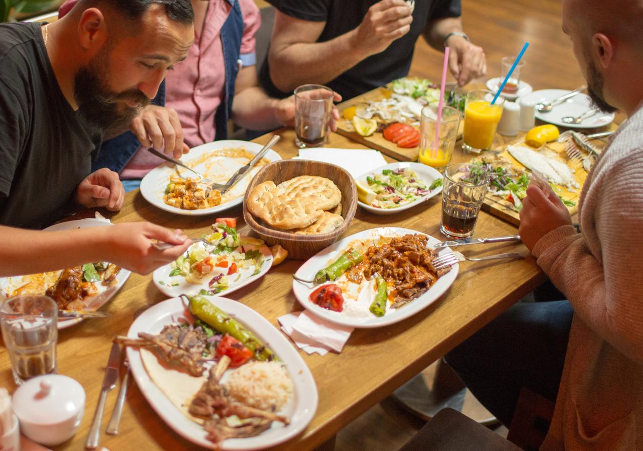 A group of diners share grilled meats, salads, and bread at a traditional restaurant in Istanbul, Türkiye, accessed July 18, 2025. (Adobe Stock Photo)