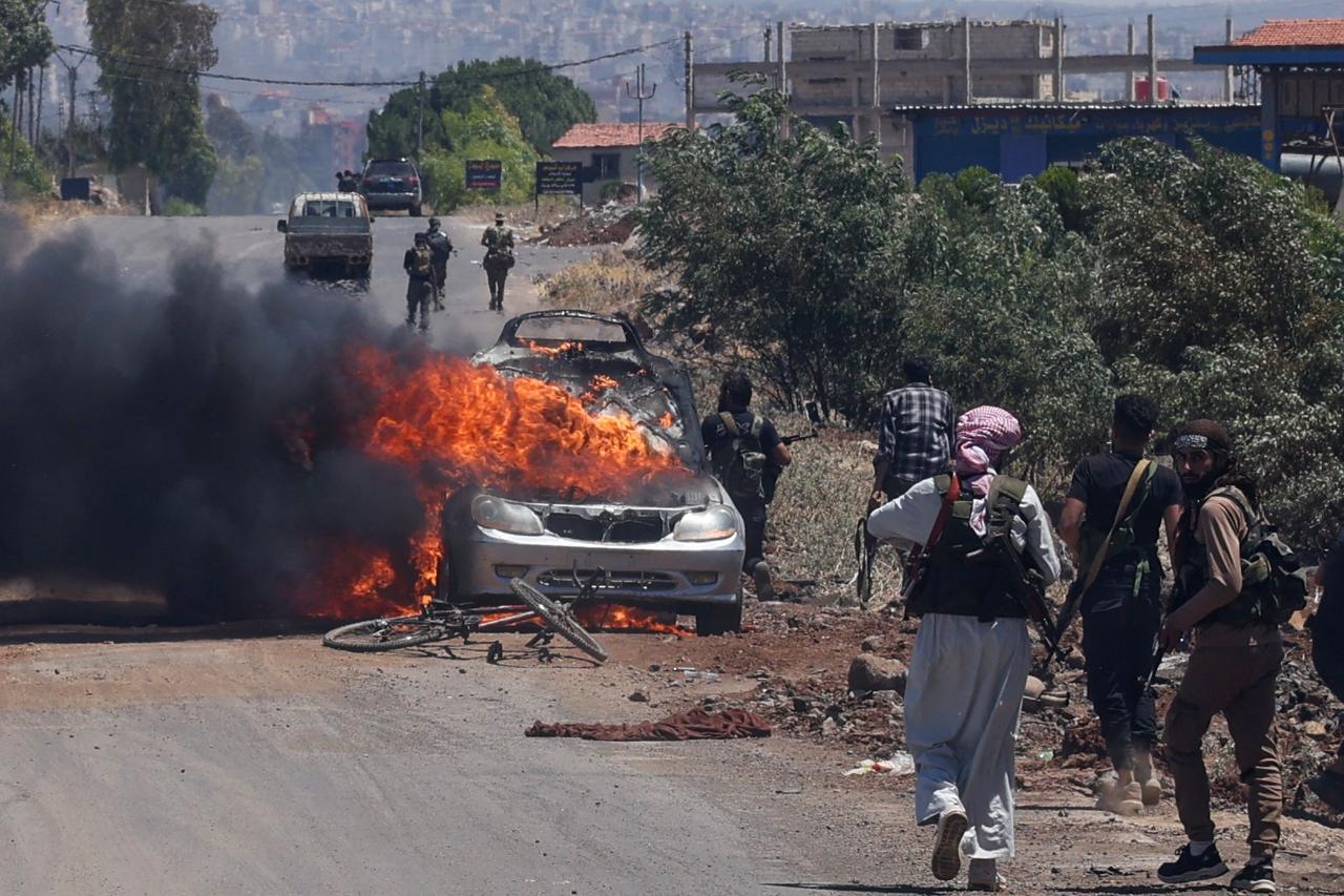 Bedouin and tribal fighters deploy as a car burns at the western entrance of Syria's Druze heartland of Sweida on July 18, 2025. (AFP Photo)