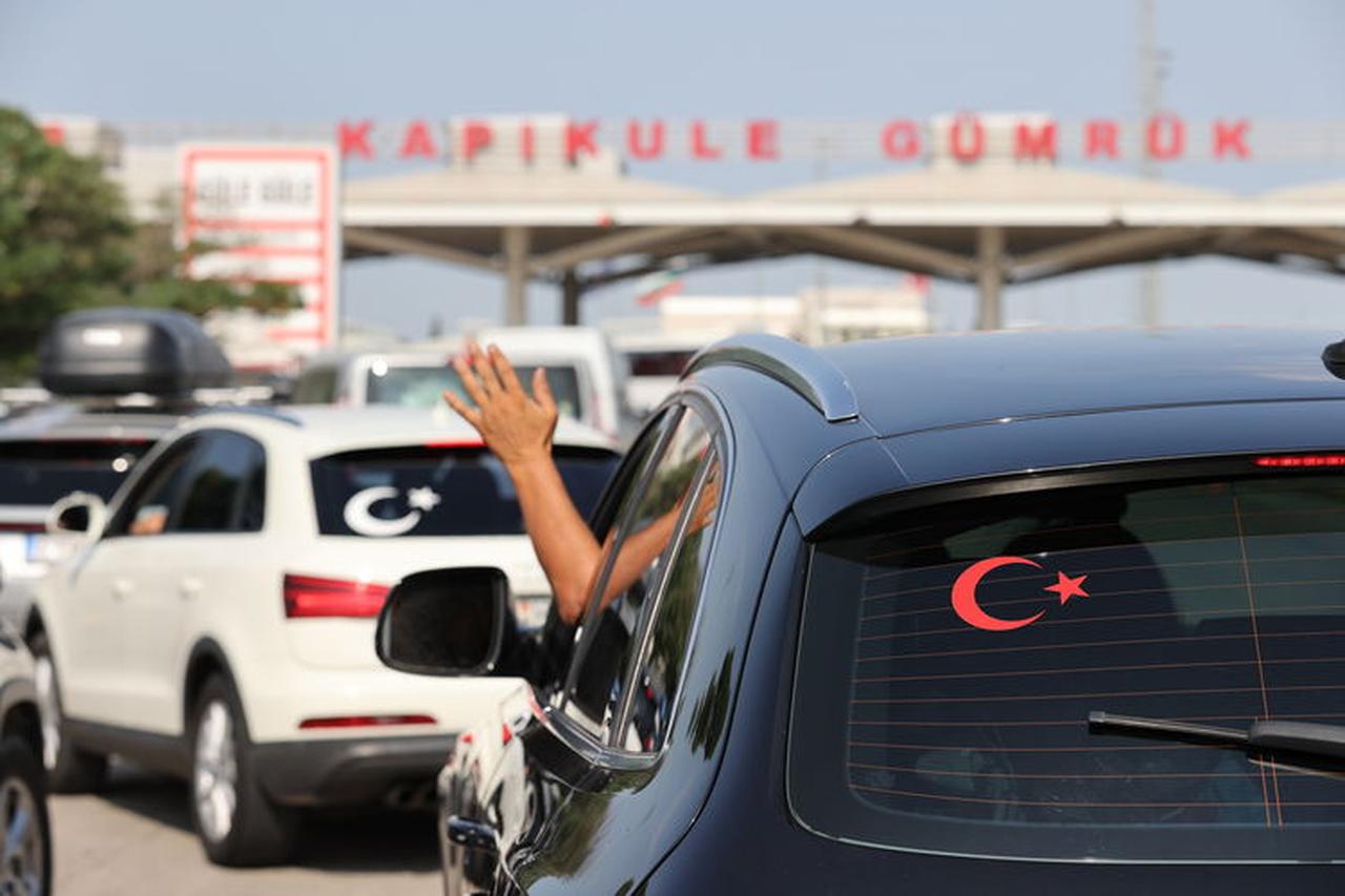 A person waves from a car adorned with a Turkish flag sticker while entering Türkiye through the Kapikule border gate in Edirne. (AA Photo)