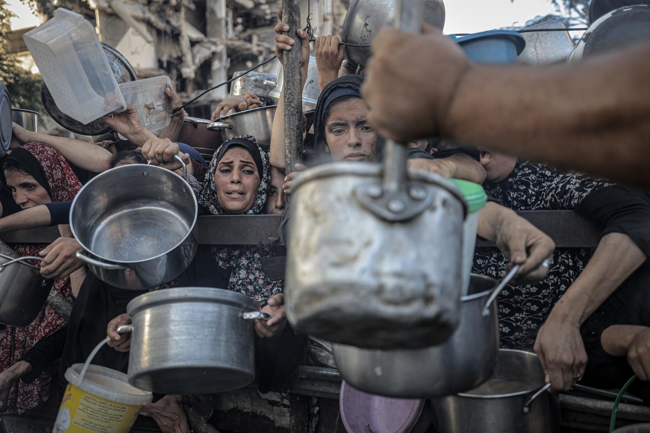 Palestinians, including children wait in line to receive hot meals distributed by the charity organization in Gaza City, Gaza on July 20, 2025. (AA Photo)