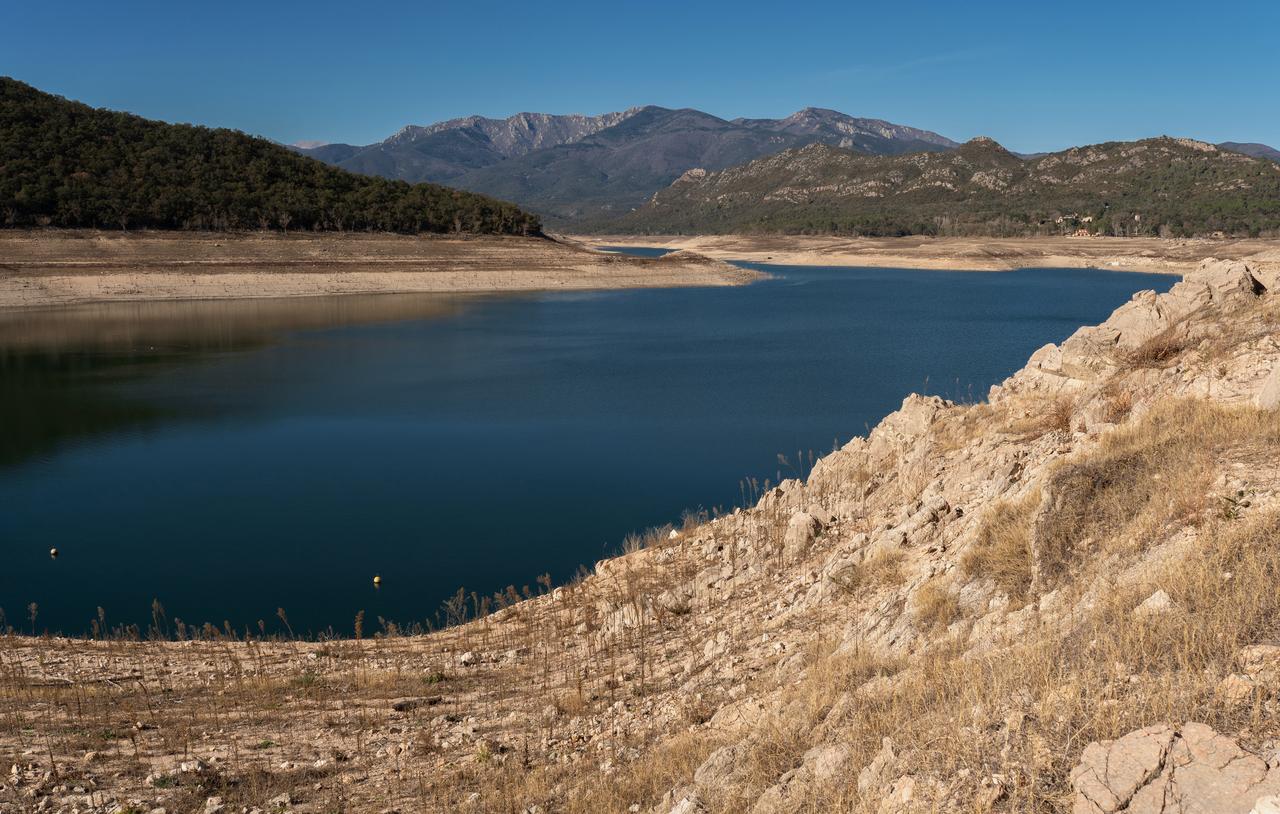 Wide view of a nearly empty reservoir in Darnius, Catalonia, Spain, surrounded by rocky hills and mountains during a drought. (Adobe Stock Photo)