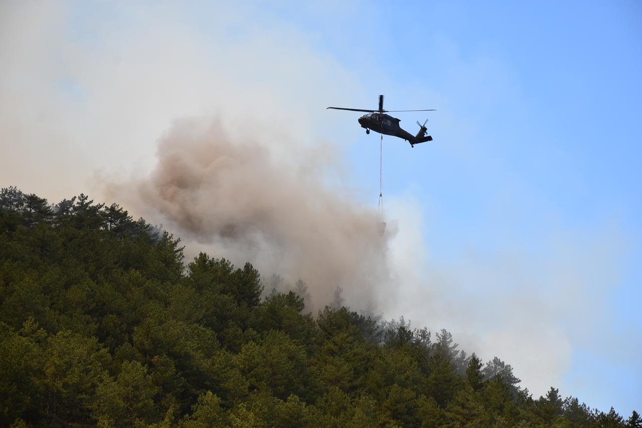 ESKISEHIR, TURKIYE - JULY 22: A helicopter carries water to extinguish fire as smoke from the fire area fills the sky while air and land intervention continues against the fire that broke out in the forest area in Seyitgazi district of Eskisehir, Turkiye on July 22, 2025.  ( Atahan Gezer - Anadolu Agency )