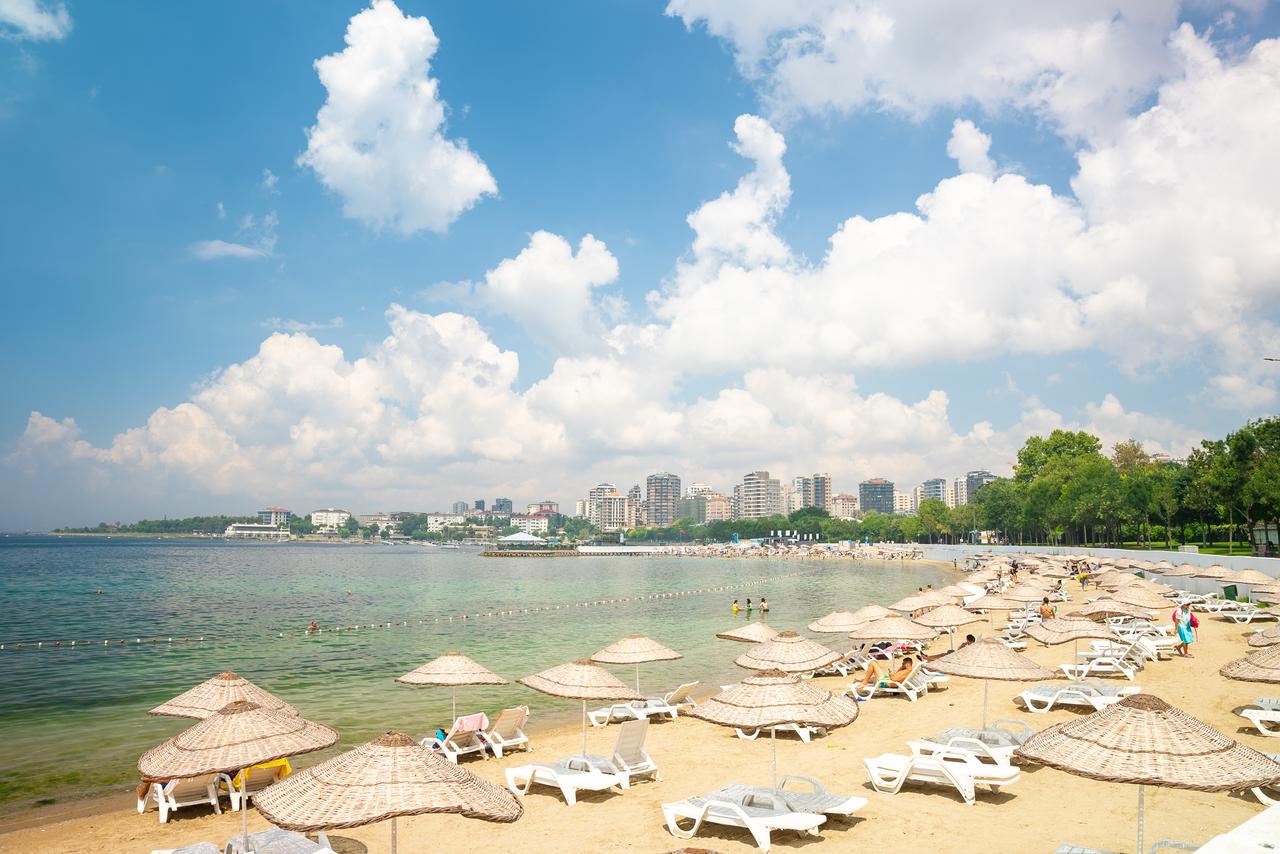 Citizens enjoying swimming and sunbathing under umbrellas on the sandy shores of Caddebostan on a sunny summer day. (Adobe Stok Photo)