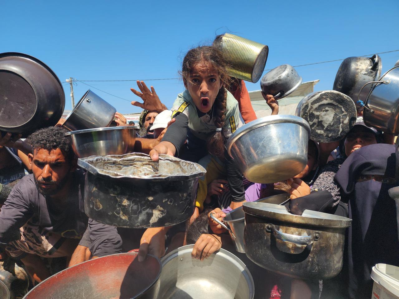 Palestinians struggling with hunger crowd around as a charity distributes food in the Al-Mawasi area of Khan Yunis, Gaza amid ongoing Israeli restrictions blocking humanitarian aid from reaching Gaza, on July 24, 2025. (AA Photo)