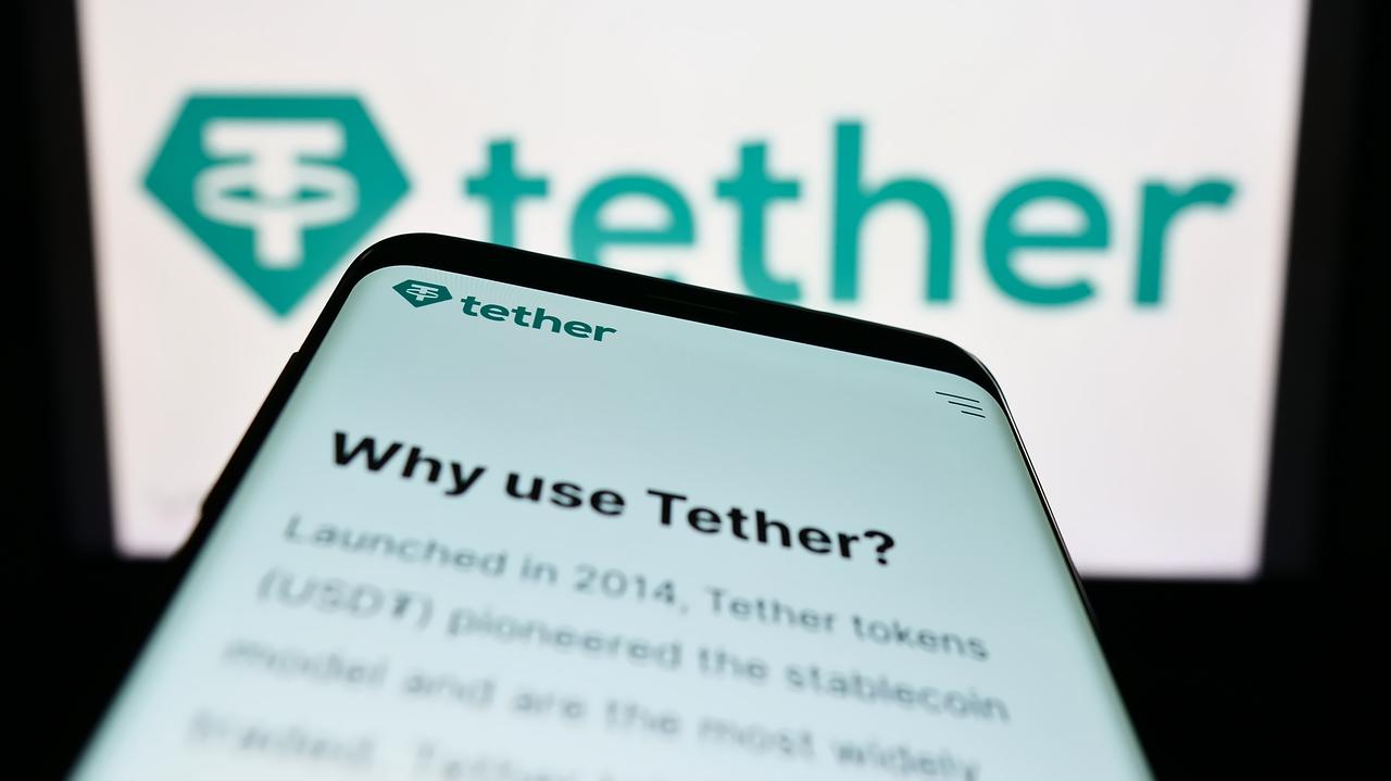 Photo illustration shows a smartphone displaying a page from Tether's website with the company's logo in the background. (Adobe Stock Photo)