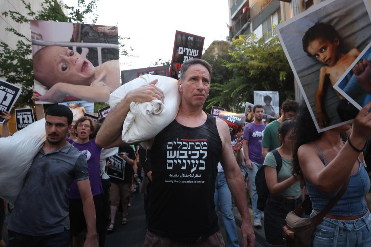 Demonstrators gather to protest and draw attention to the hunger crisis in Gaza, carrying flour sacks on their shoulders as a symbol of the urgent need for food aid in Tel Aviv, July 22, 2025. (Photo via AA).