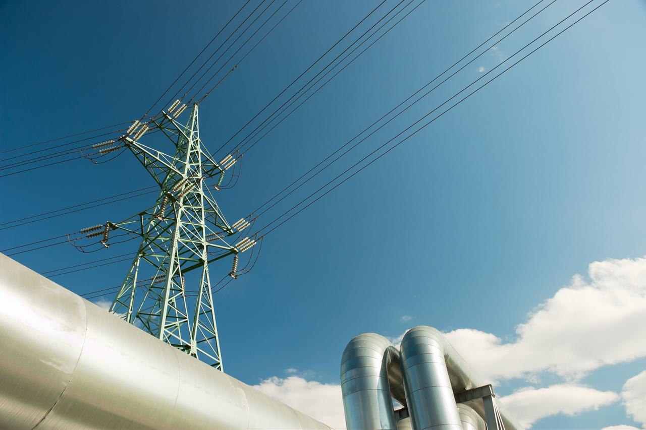 A high-voltage transmission tower and insulated energy pipelines. (Adobe Stock Photo)