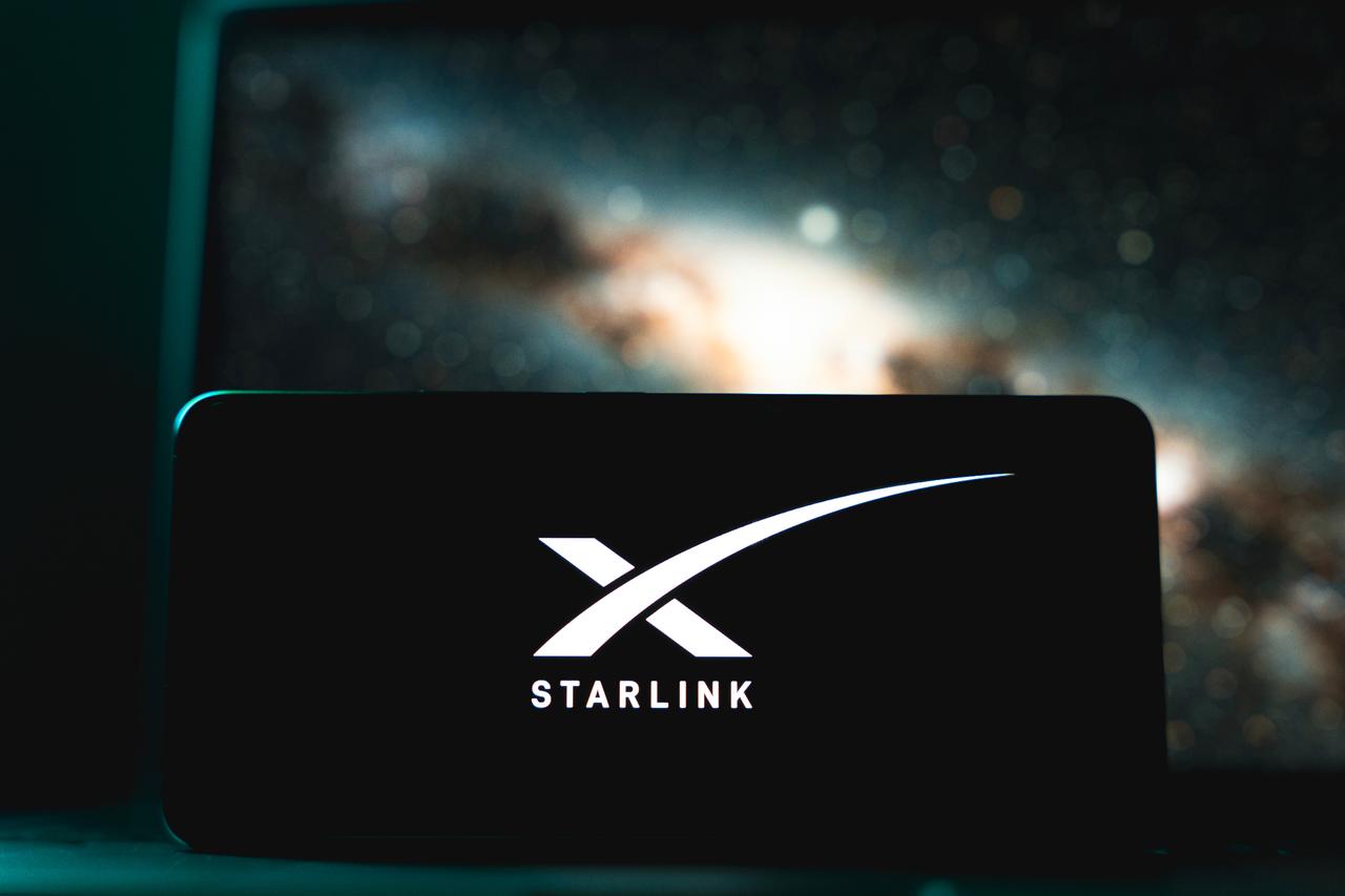 Starlink logo displayed on screen with a space-themed background (Adobe Stock Photo)
