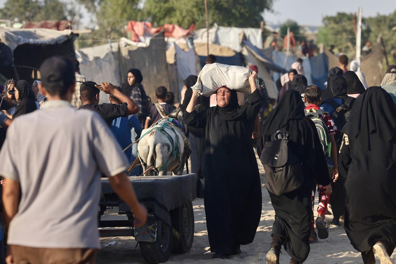 A Palestinian woman carries a bag of aid on hear head as she makes her in the Mawasi area of Rafah on July 24, 2025. (AFP Photo)
